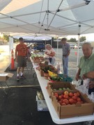 farmers market; boxes of veggies and people selling them