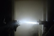 SWAT officers using flashlights on guns to see in a hazy room