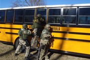 SWAT officers helping another officer through window of school bus